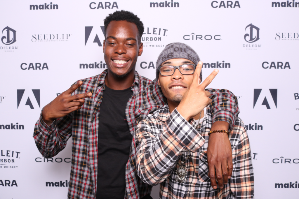 Two guests at a multi-brand step-and-repeat featuring Adobe, Cîroc and Bulleit Bourbon