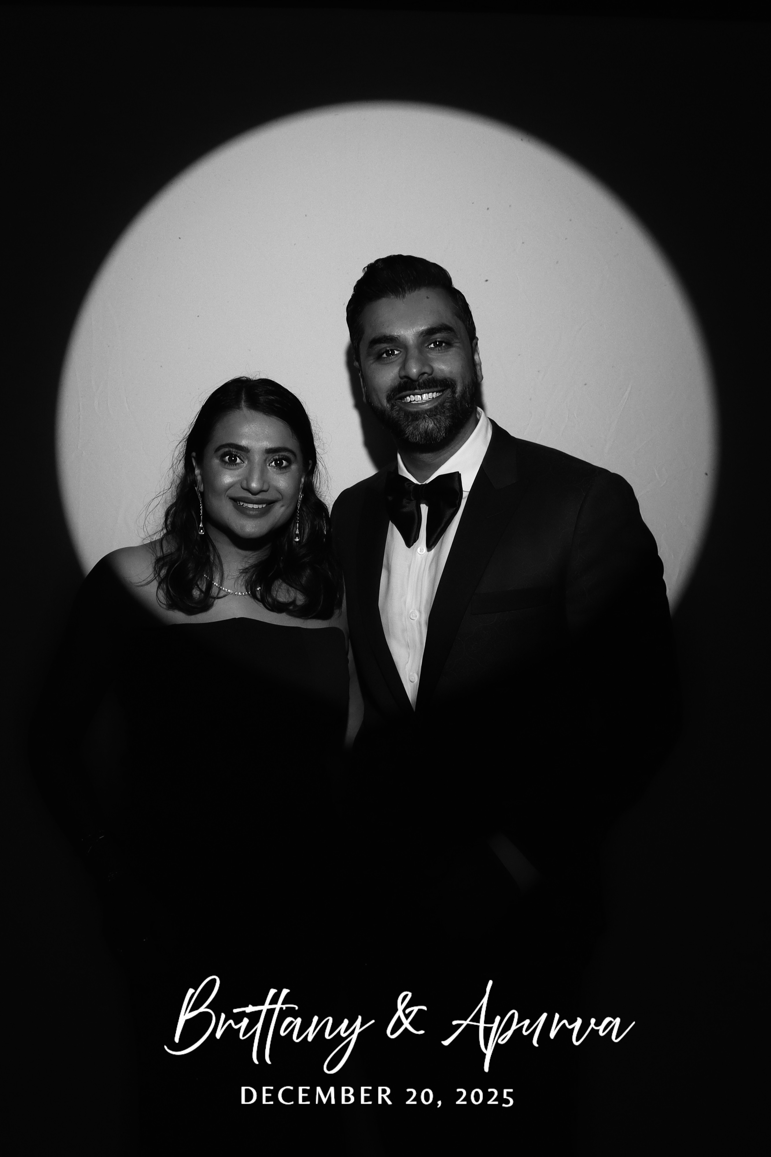 Black and white spotlight portrait of a couple in a tuxedo and strapless gown