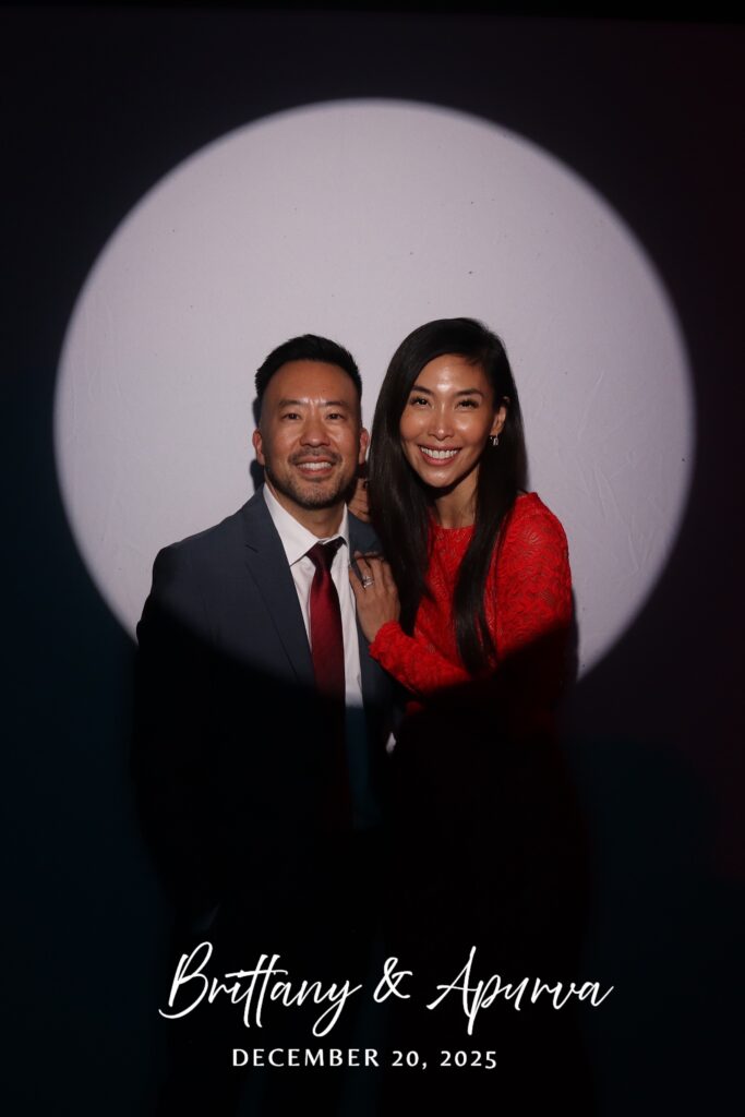 Wedding guests in a grey suit and red lace dress lit by the spotlight beam
