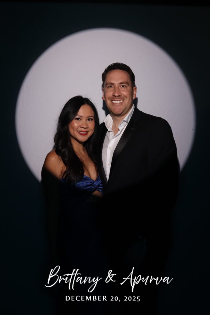 Couple in a blue gown and black tuxedo centered in the spotlight beam