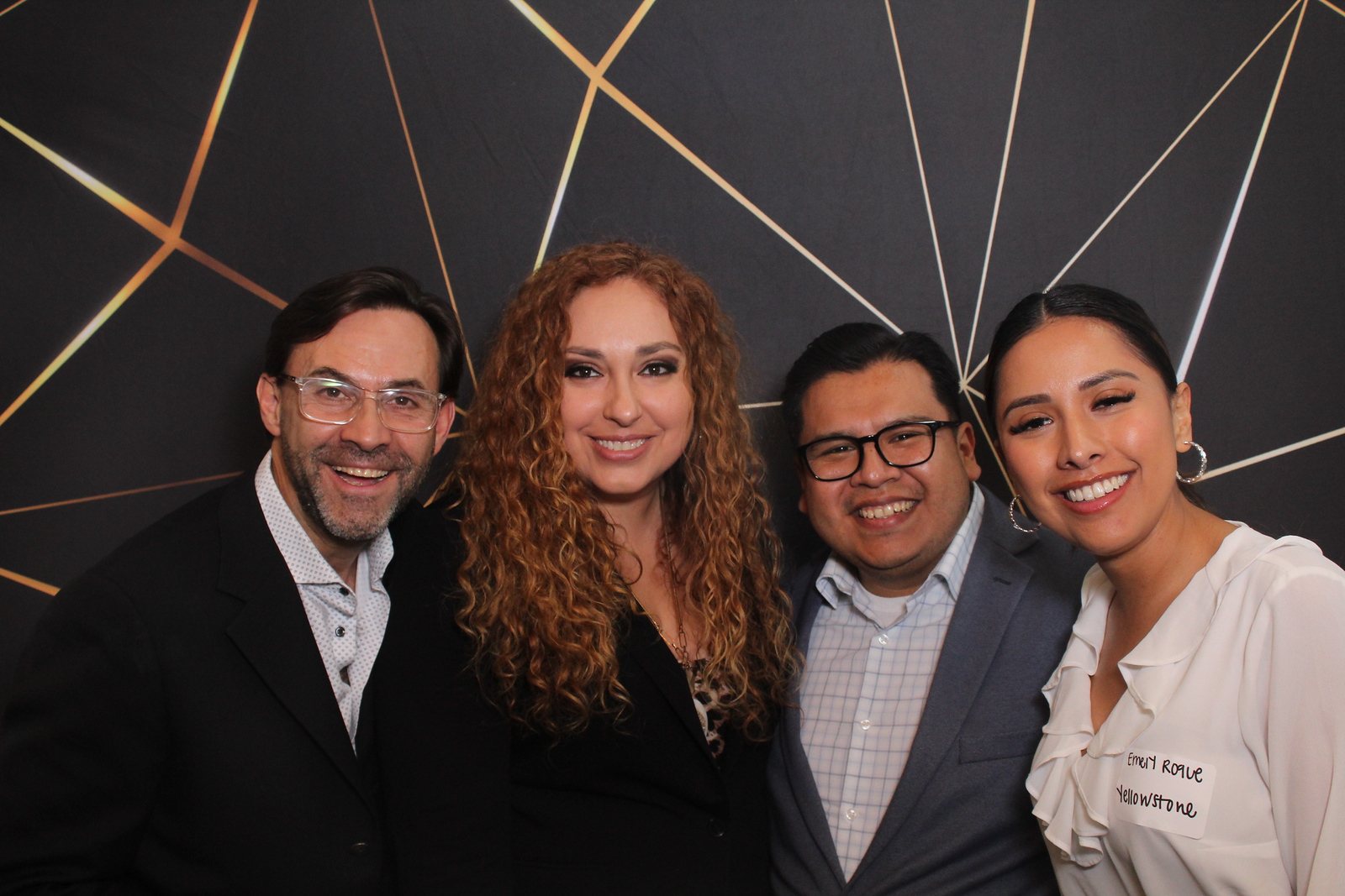 Group of colleagues at a Houston corporate event photo booth with a black and gold backdrop