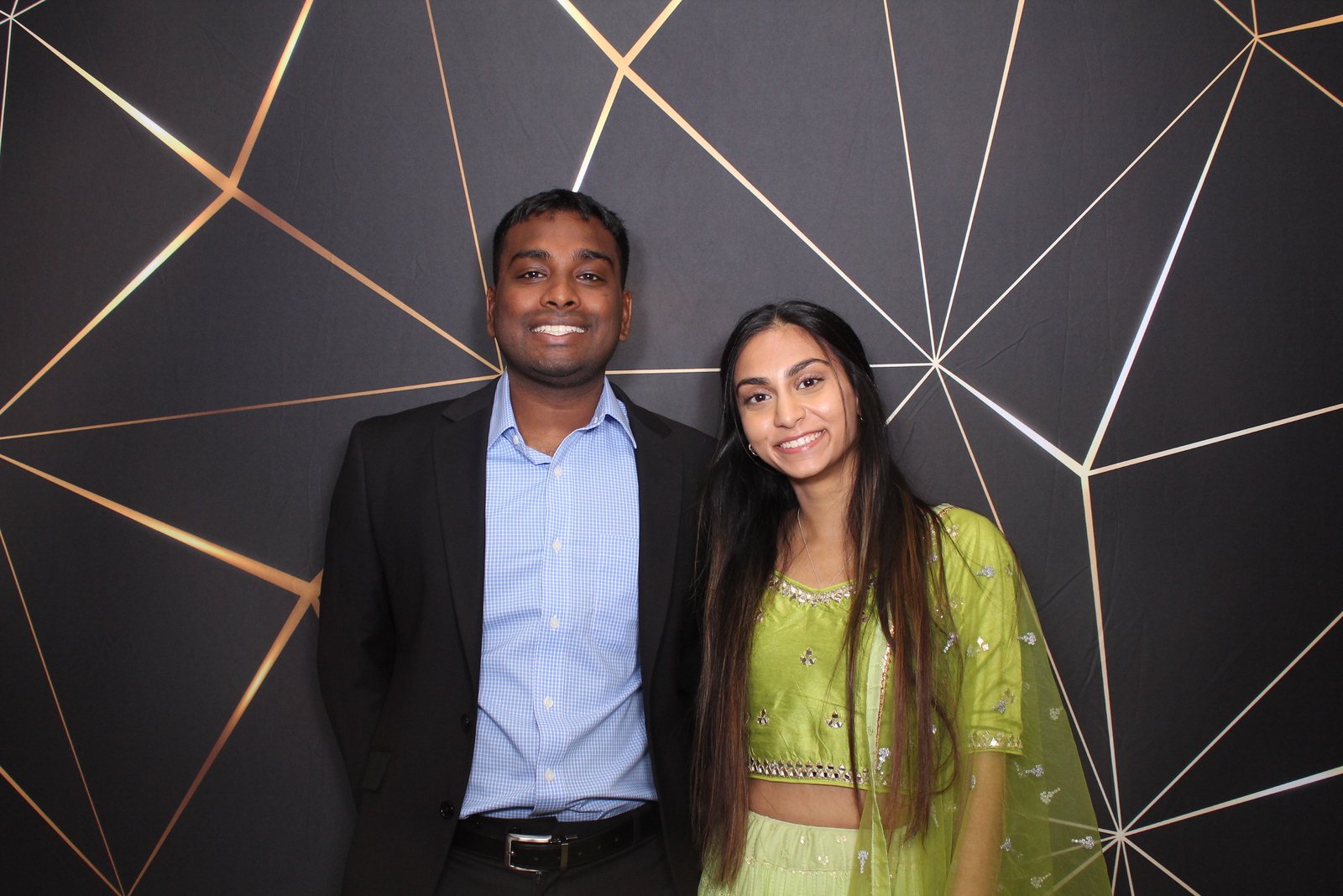 Couple at a Houston event photo booth with a gold geometric backdrop