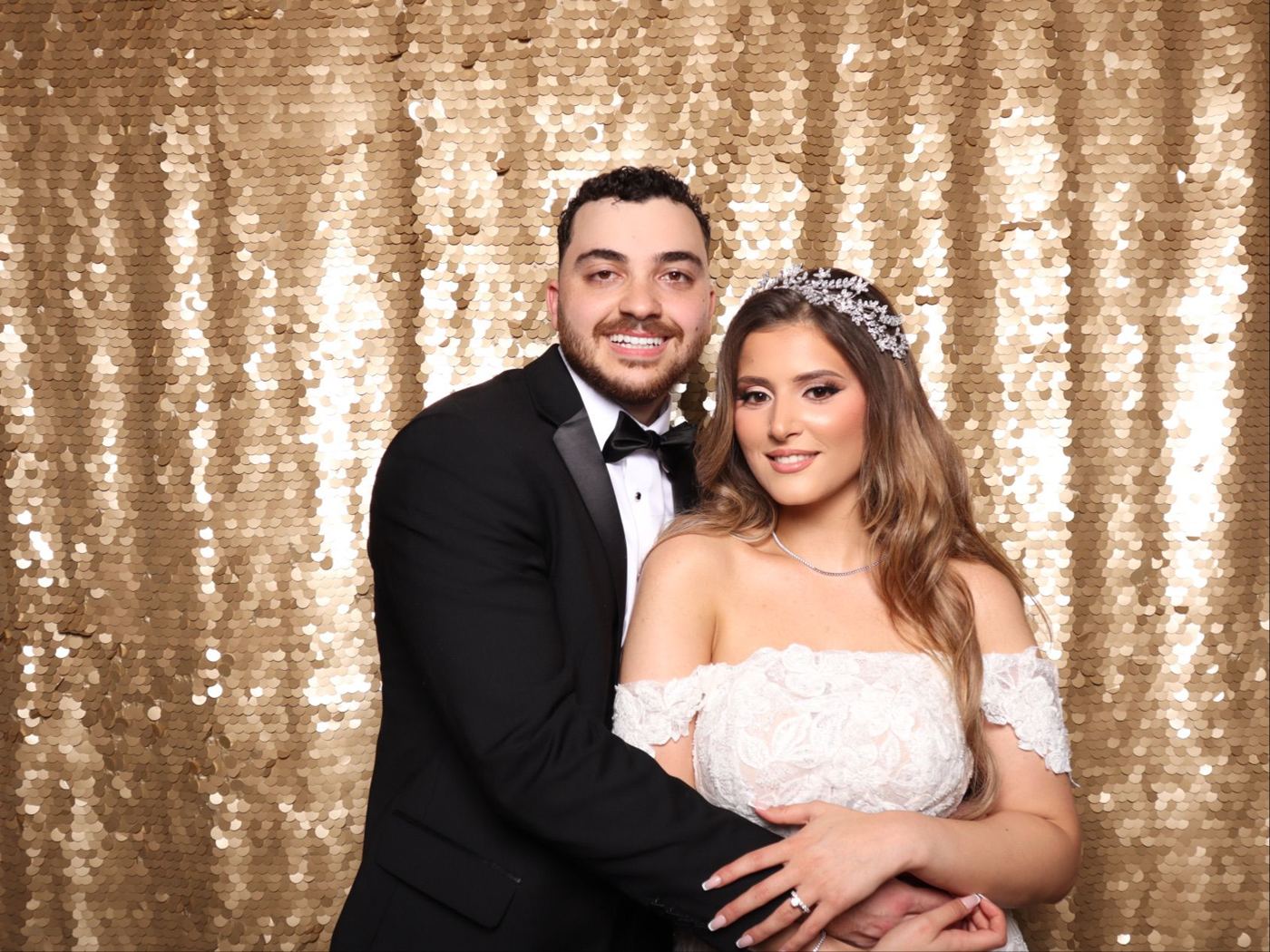 Bride and groom posing in front of a gold sequin backdrop in the Open Air Booth at a Houston wedding