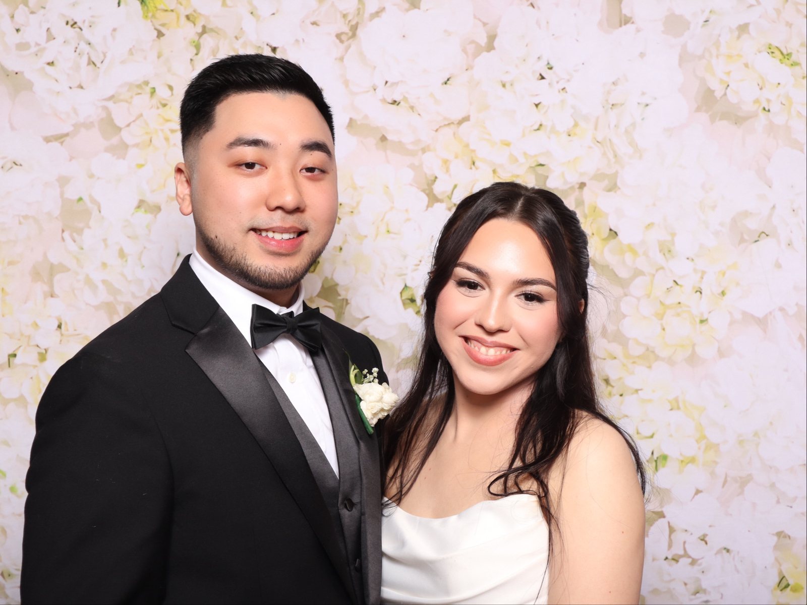Bride and groom at a wedding photo booth in Houston with a white floral backdrop